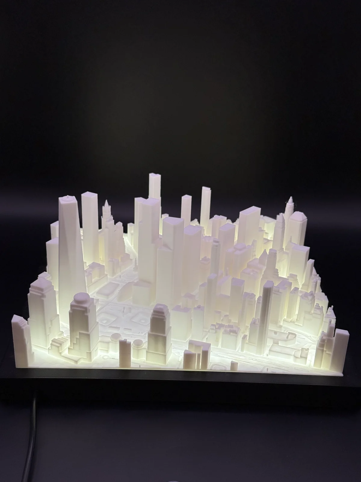 Maquette blanche de Manhattan imprimée en PLA sur un socle noir, avec son éclairage LED allumé.
